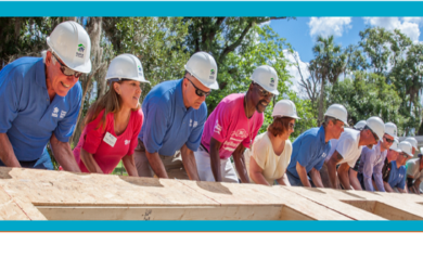 Workers lifting a wall in place to build a house