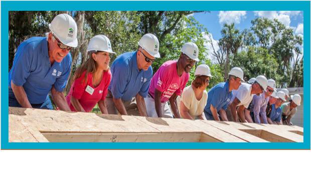 Workers lifting a wall in place to build a house