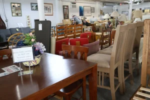 Wood dining table set with chairs and a floral centerpiece in the Habitat ReStore Sebring furniture aisle