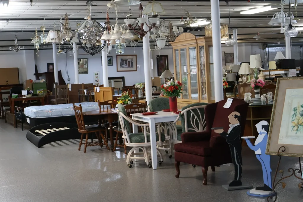 Wide view of Habitat ReStore Sebring showroom with chandeliers, dining tables, chairs, and accent furniture